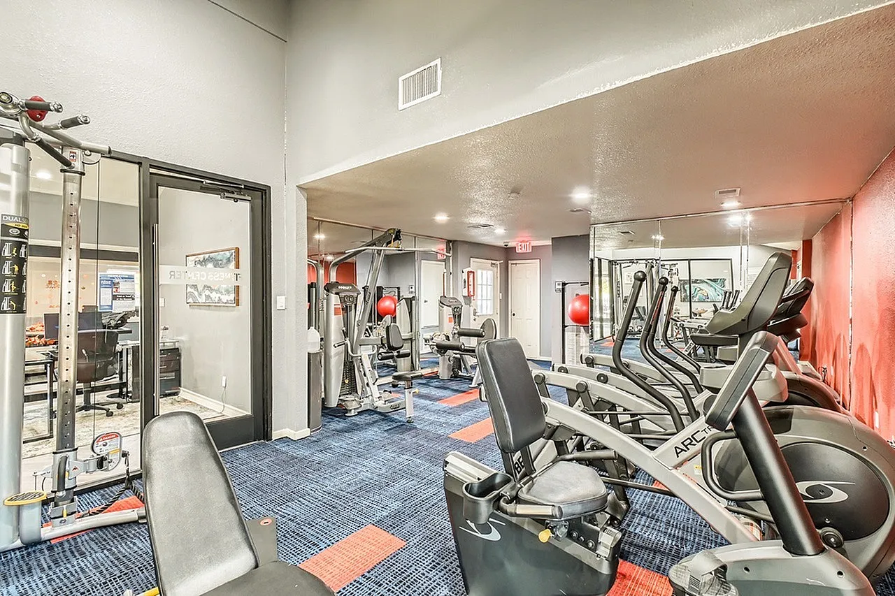 Fitness center, cardio machines, mirrored walls, blue and orange flooring