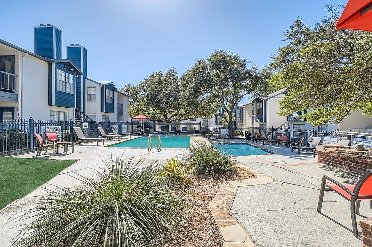 Resort-style swimming pool, lounge seating, manicured lawn, mature trees