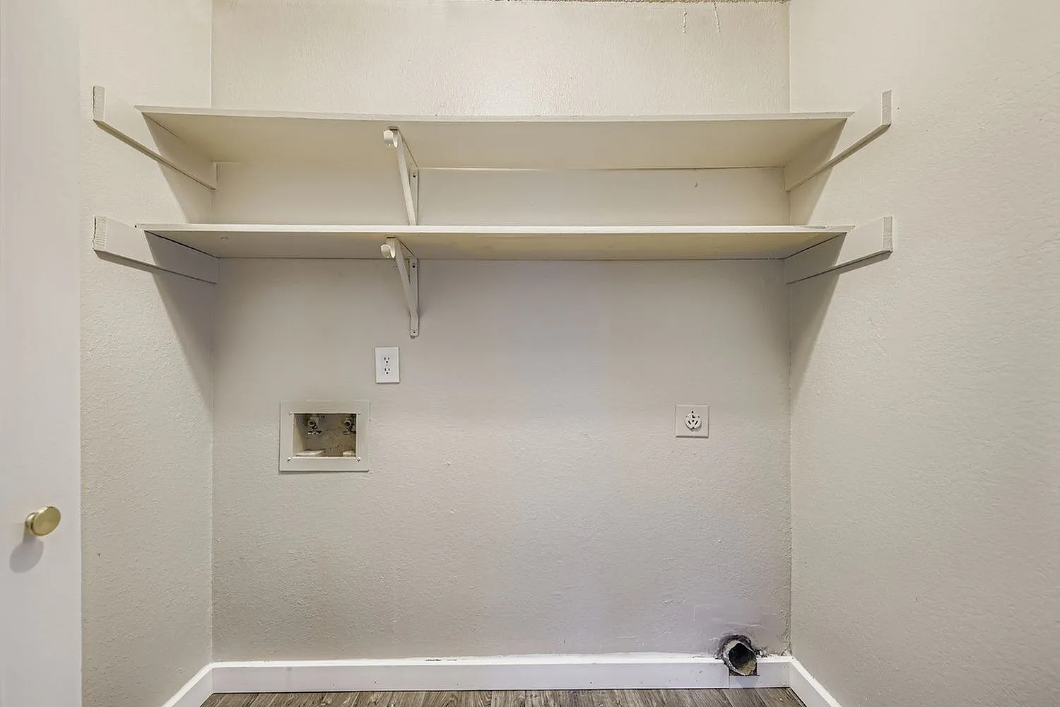 Laundry room, two white floating shelves, electrical outlet, wood-style plank flooring