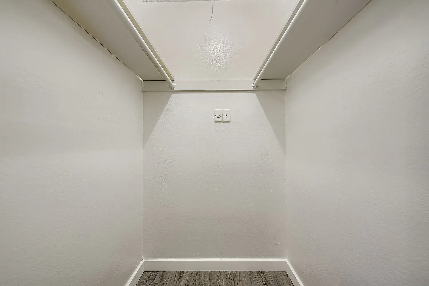 Closet, white walls, wood-style plank flooring, light fixture, wall outlet
