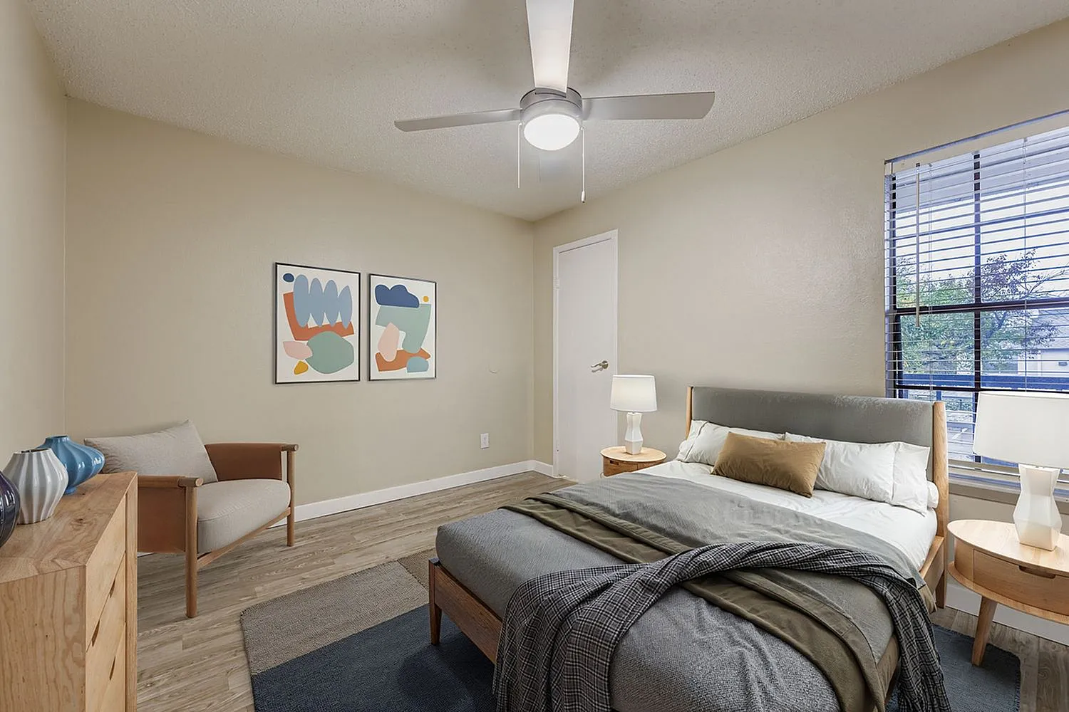 Primary bedroom, wood-style plank flooring, ceiling fan, wood nightstands, window blinds