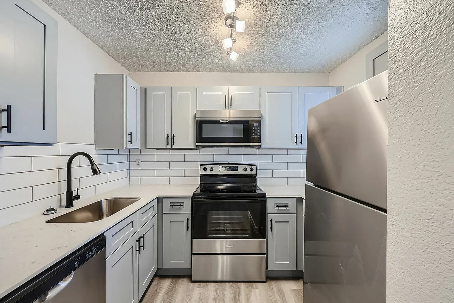 Kitchen, gray shaker cabinetry, white subway tile backsplash, stainless steel appliances, wood-style plank flooring