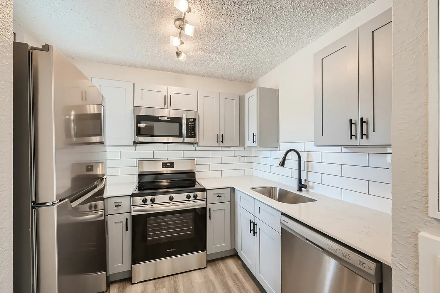 Kitchen, white shaker cabinetry, subway tile backsplash, stainless appliances, wood-style plank flooring