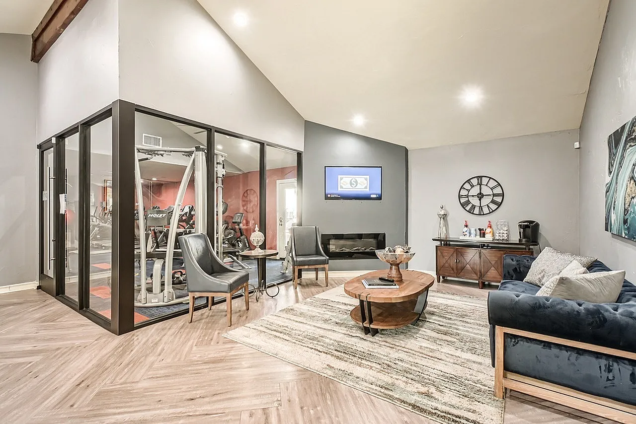 Living room, wood-style plank flooring, modern fireplace, framed gym enclosure, sectional sofa