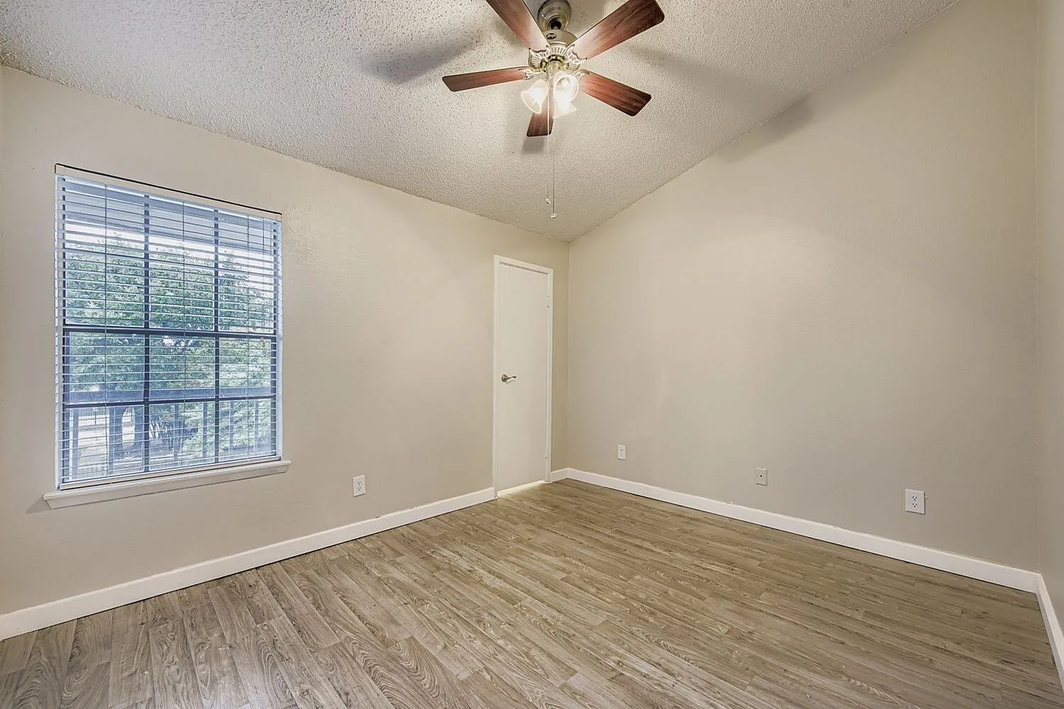 Bedroom, wood-style plank flooring, ceiling fan, large window, white door