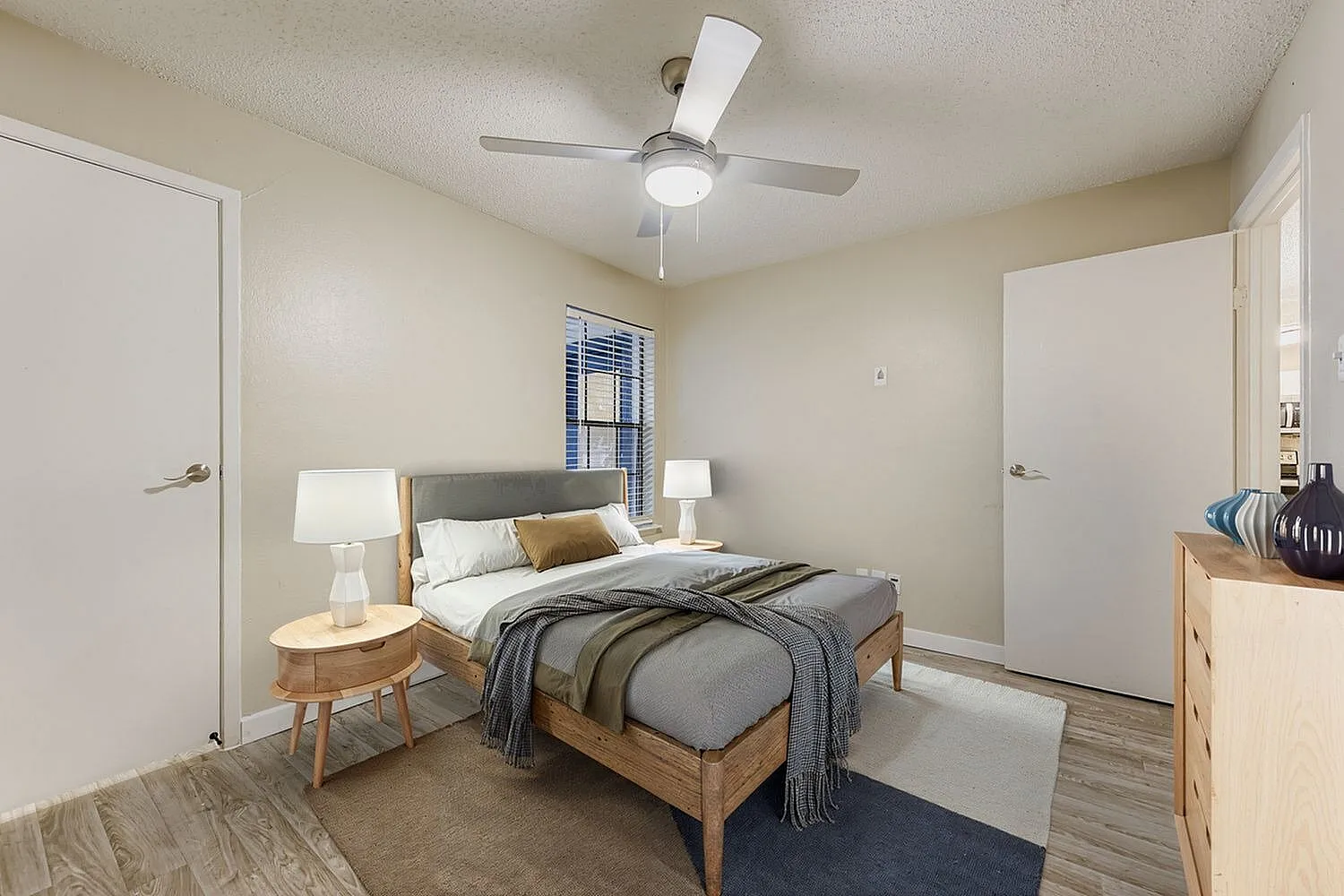 Primary bedroom, wood-style plank flooring, ceiling fan, wooden bed frame, bedside nightstand