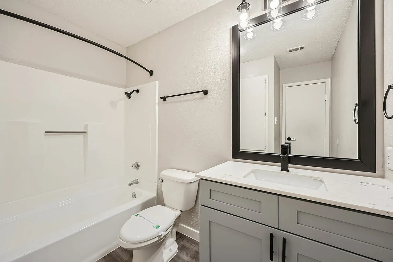 Bathroom, gray cabinetry, white quartz countertop, framed mirror, chrome fixtures, white subway tile