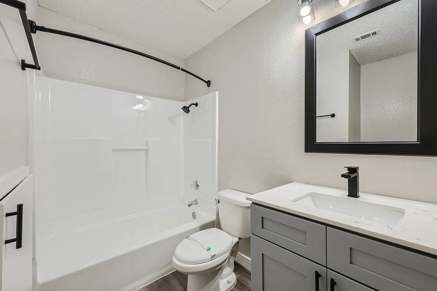 Bathroom, gray cabinetry, white countertops, framed mirror, black fixtures