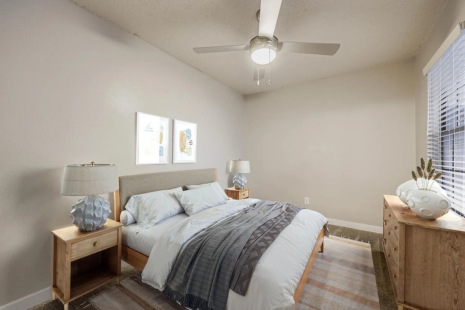 Primary bedroom, wood-style plank flooring, ceiling fan, windows with shutters, wood nightstands