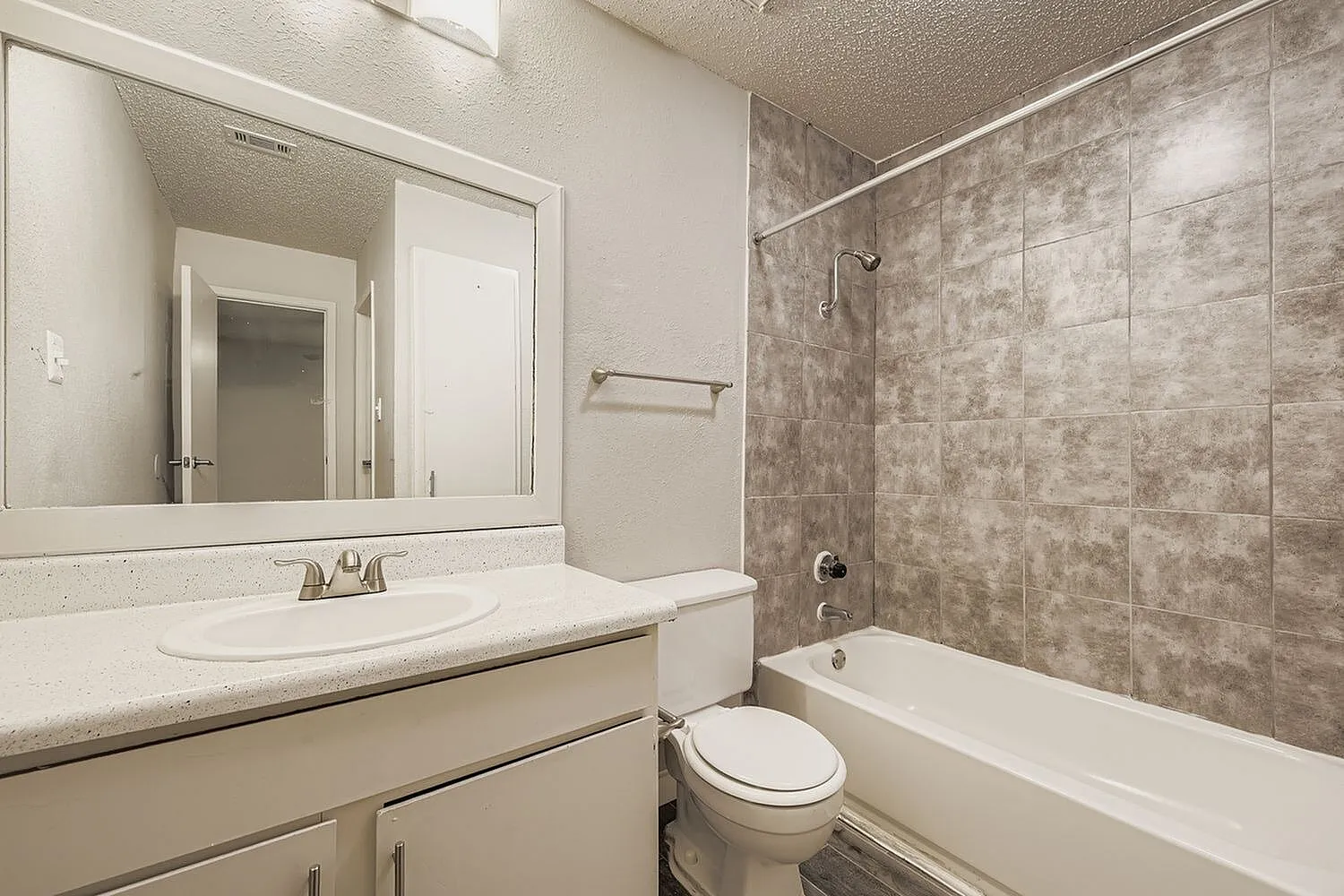 Bathroom, white vanity with round sink, framed mirror, gray tile shower surround