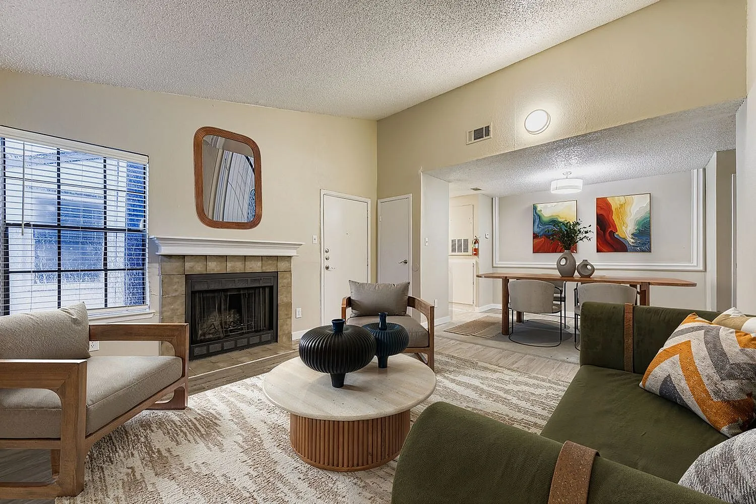 Living room, wood-style plank flooring, fireplace, green upholstered seating, wood accent furniture