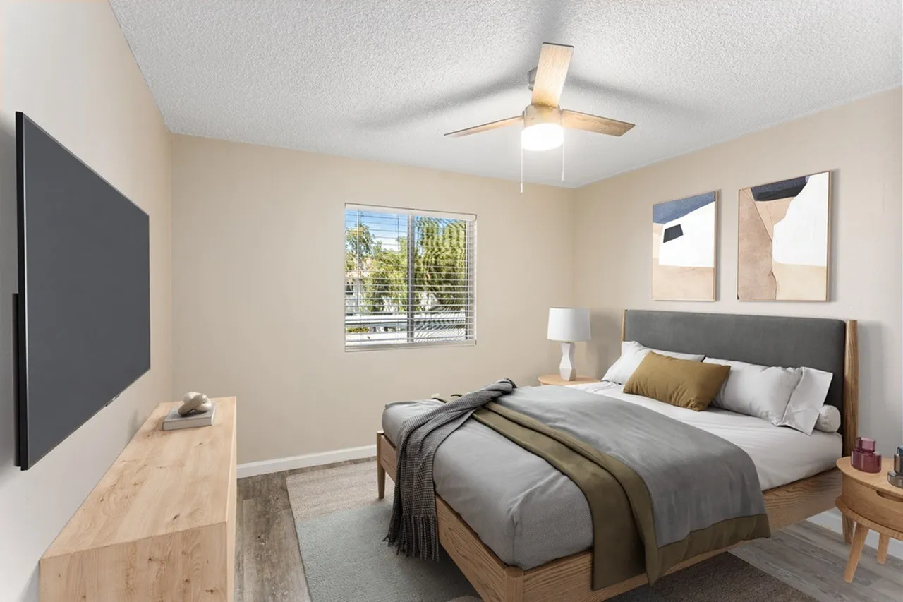 Primary bedroom, gray upholstered bed, wood-style plank flooring, ceiling fan, window
