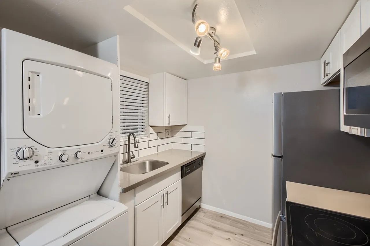 Kitchen, white shaker cabinetry, stainless steel appliances, subway tile backsplash, wood-style plank flooring, laundry appliances