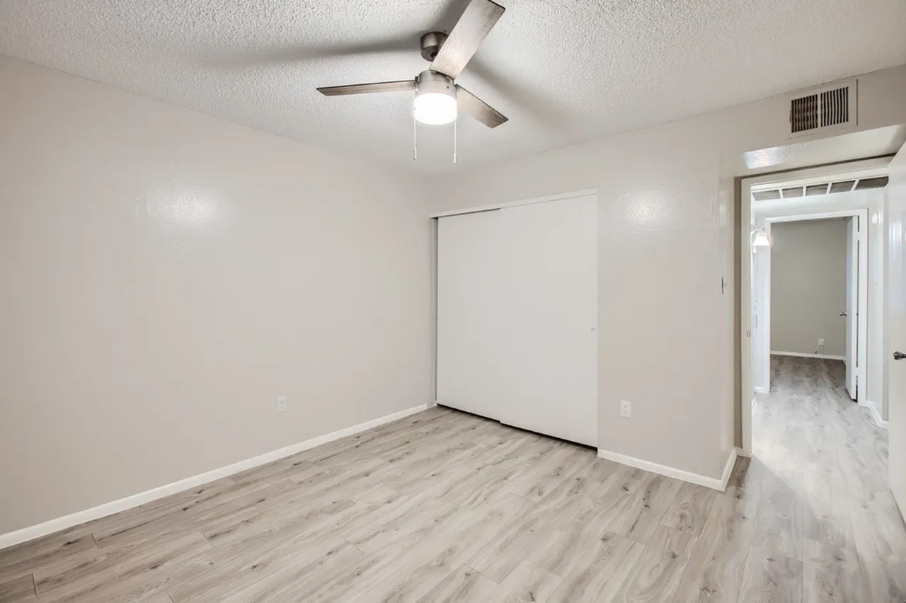Bedroom, wood-style plank flooring, ceiling fan with light, white walls, closet