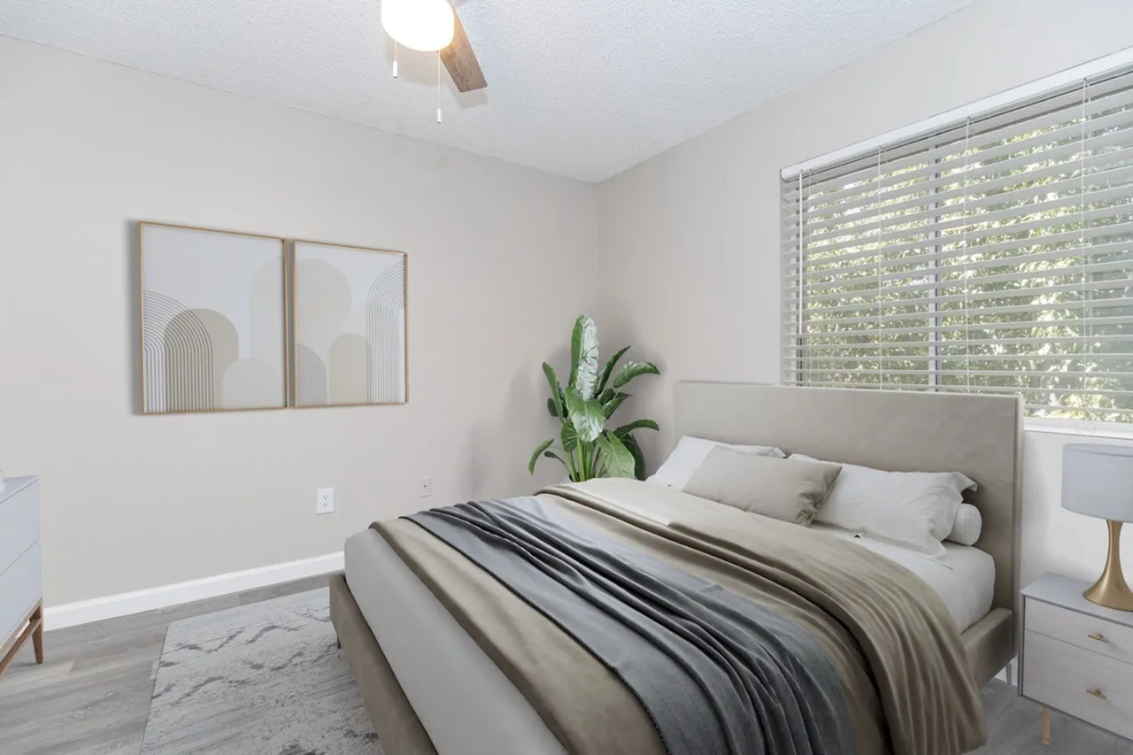 Primary bedroom, upholstered headboard, wood-style plank flooring, plantation shutters, pendant light, plant