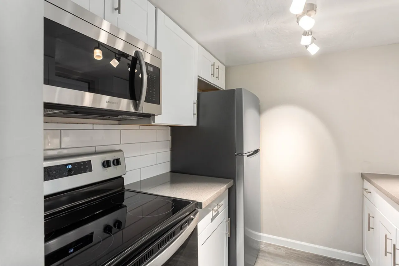 Kitchen, white shaker cabinetry, subway tile backsplash, stainless steel appliances, black refrigerator