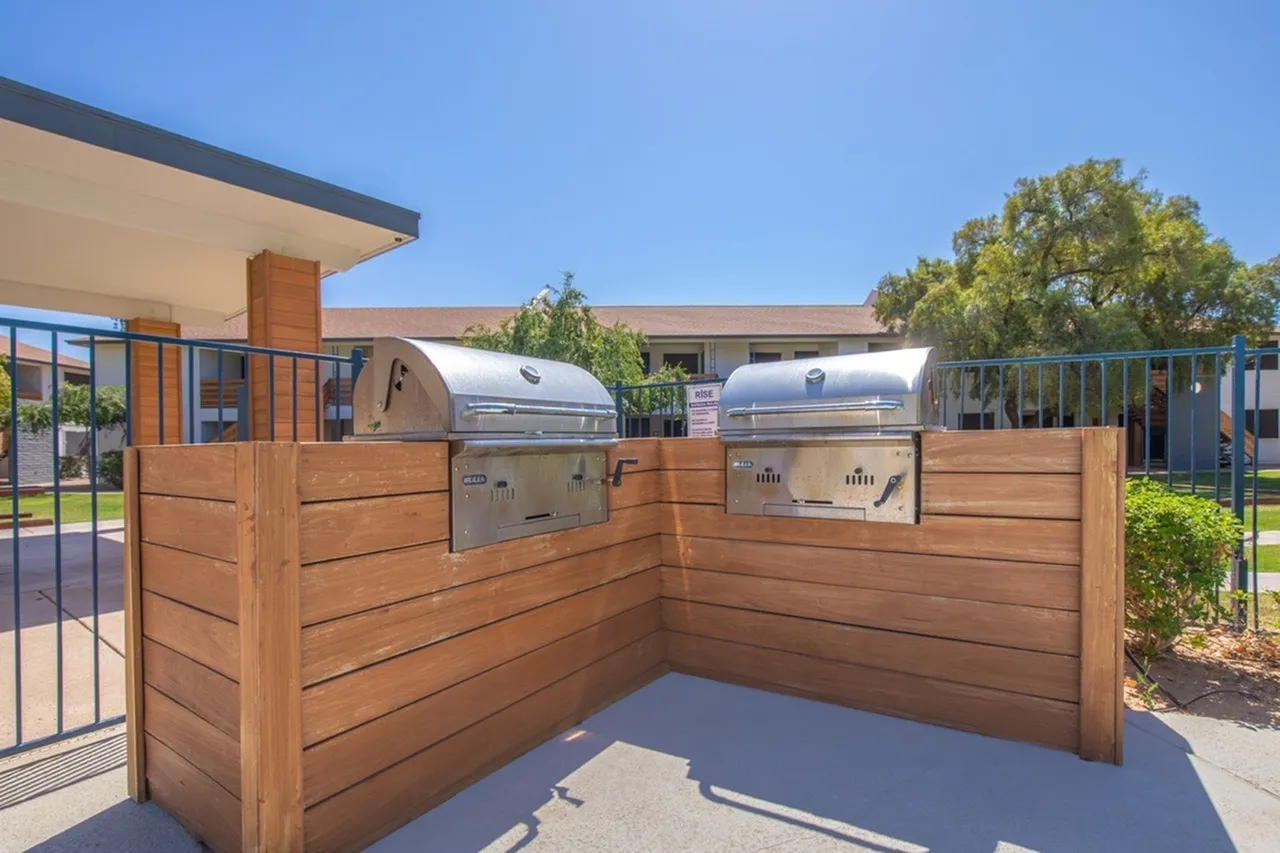 Outdoor patio with wood-style fencing, built-in stainless grill, concrete flooring, mature trees