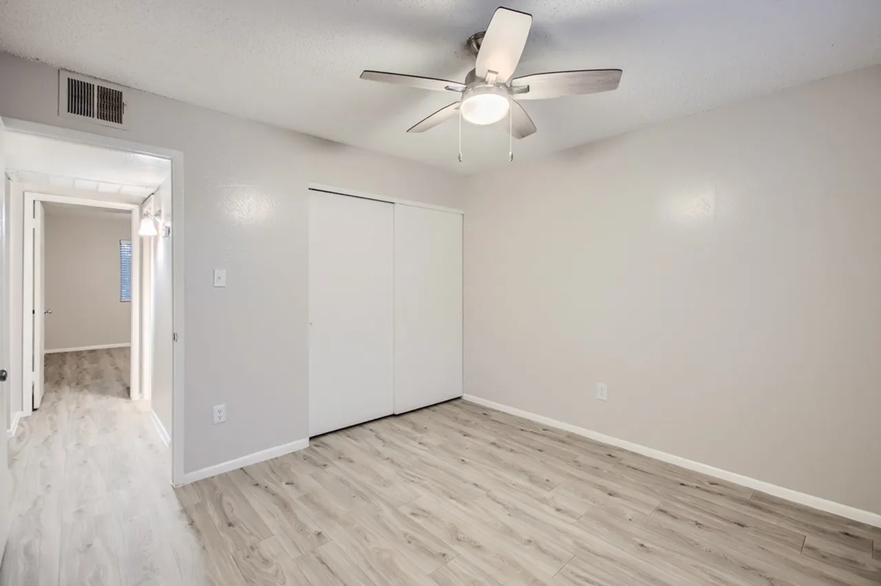 Bedroom, wood-style plank flooring, ceiling fan with light fixture, built-in closet