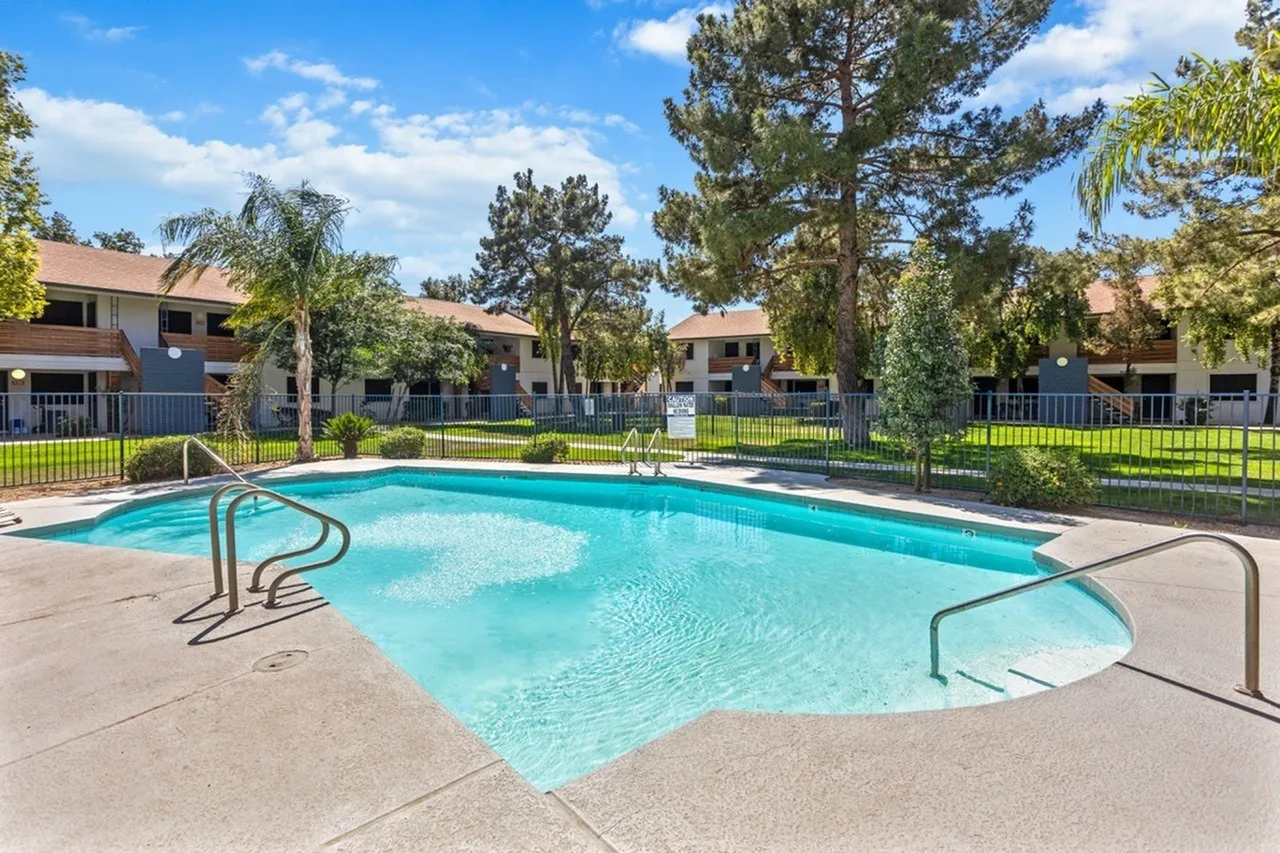 Resort pool, lounge chairs, metal railings, gated perimeter, mature trees