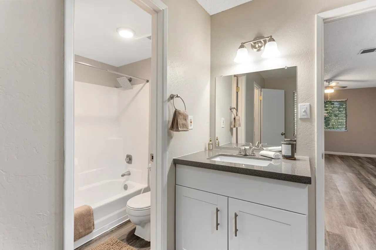 Bathroom, white vanity cabinetry, quartz countertop, framed mirror, chrome fixtures, tub shower combo