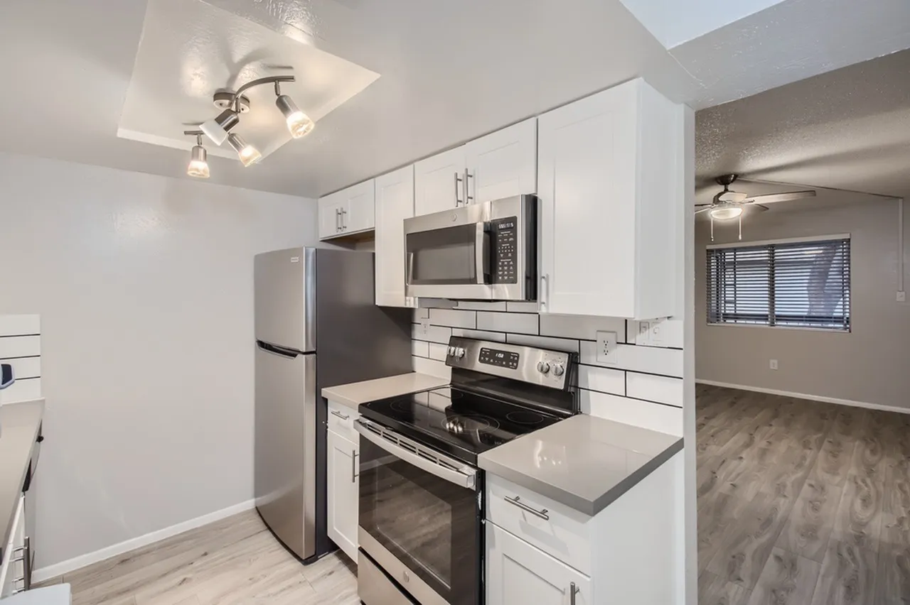 Kitchen, white shaker cabinetry, quartz countertops, stainless appliances, wood-style plank flooring
