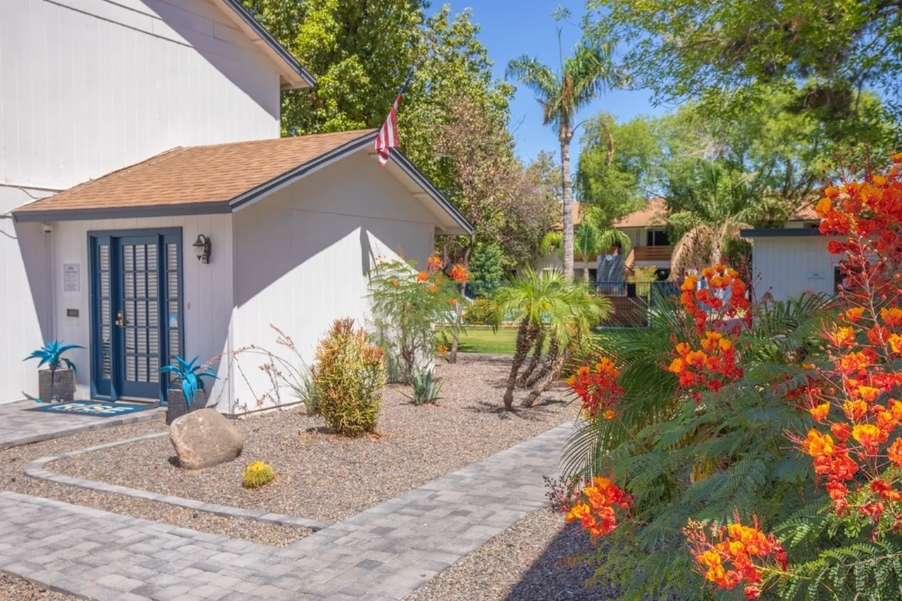 Courtyard with paver pathway, orange flowering shrubs, desert landscaping, blue door entry
