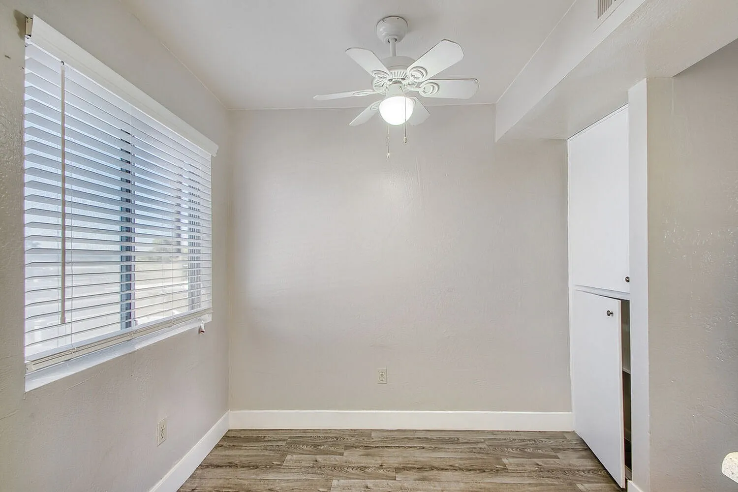 Bedroom, wood-style plank flooring, white shutters, ceiling fan with light fixture