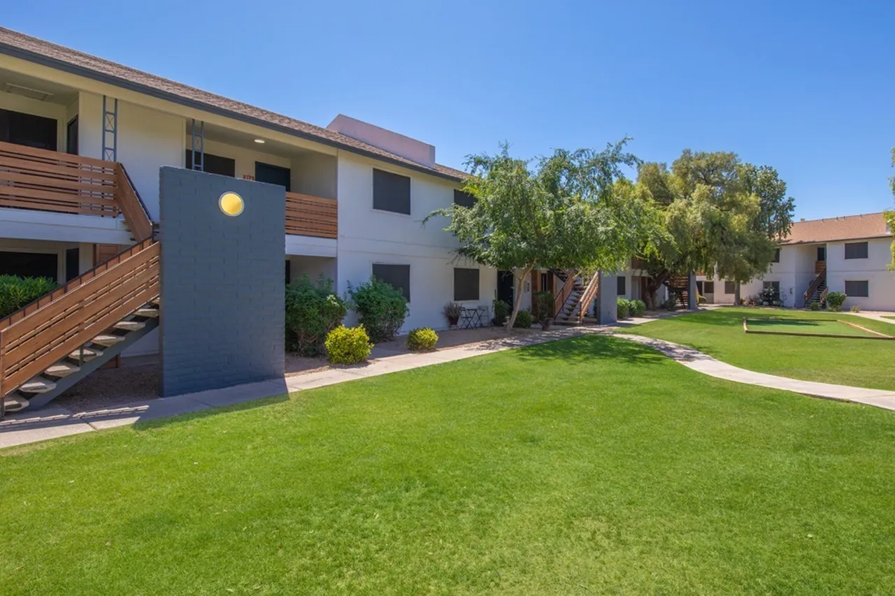 Courtyard with manicured lawn, modern building facade, wooden accent wall, modern art sculpture