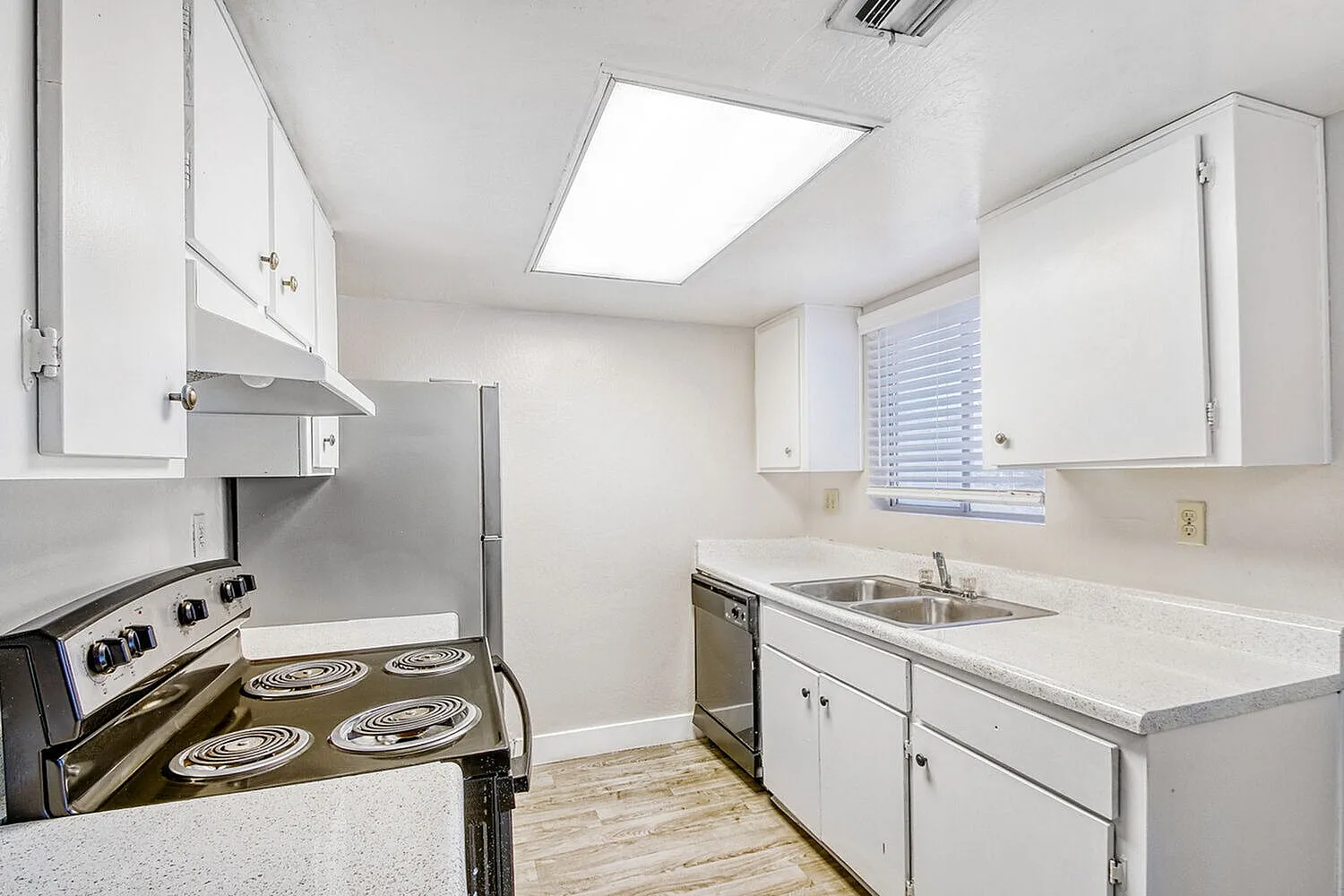 Kitchen, white cabinetry, quartz countertops, stainless appliances, wood-style plank flooring