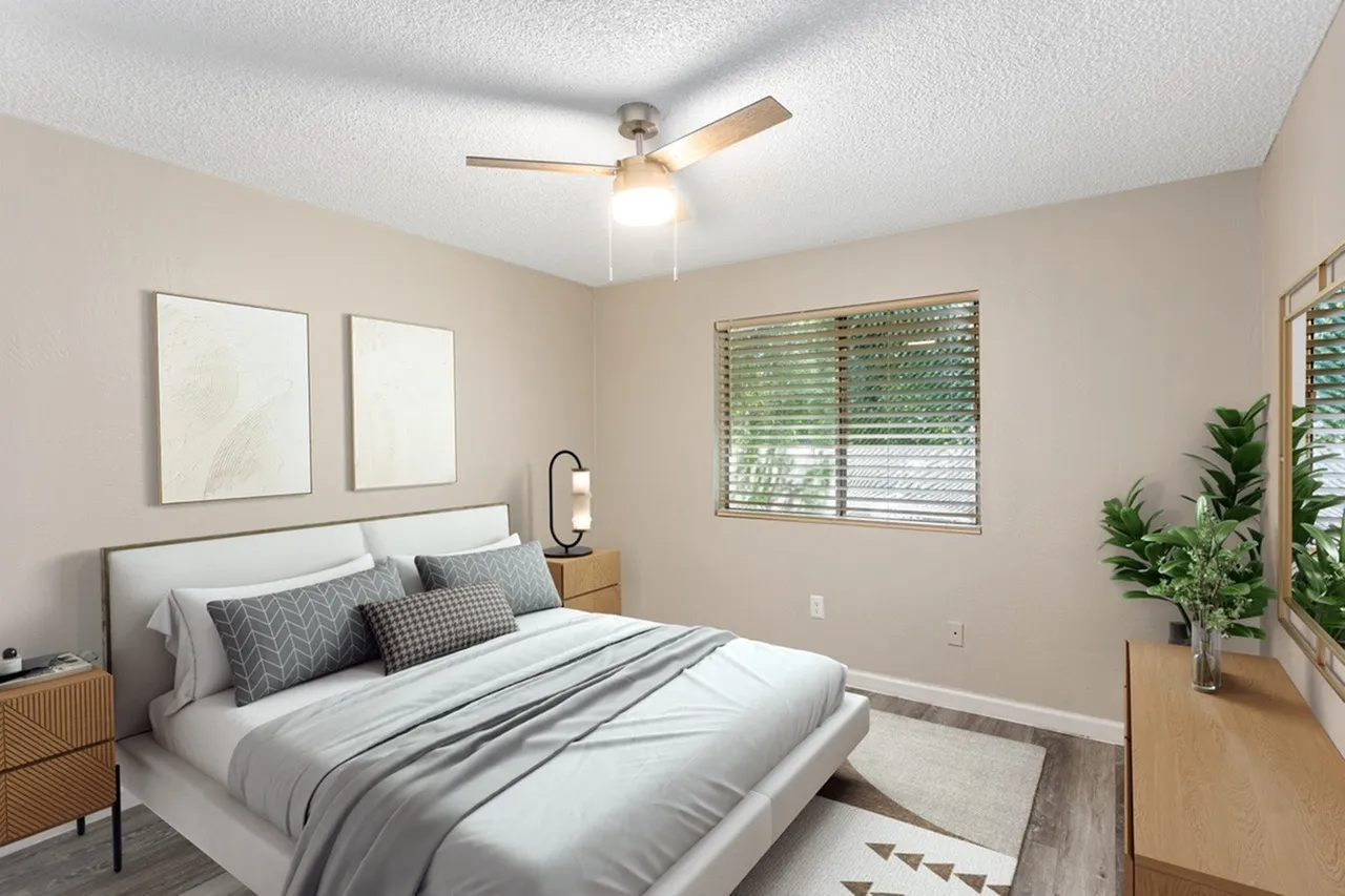 Primary bedroom, wood-style plank flooring, ceiling fan, upholstered headboard, potted plants