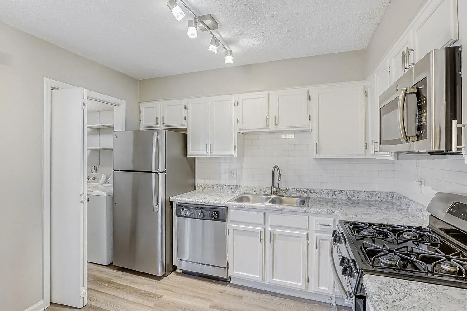 Kitchen, white shaker cabinetry, gray quartz countertops, stainless appliances, wood-style plank flooring