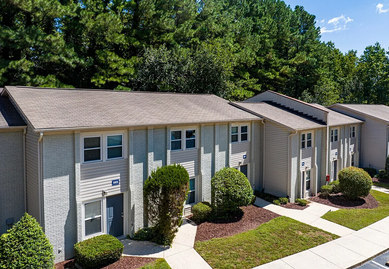 Townhouse exterior, white siding, dark shingle roof, landscaped front yard with shrubs