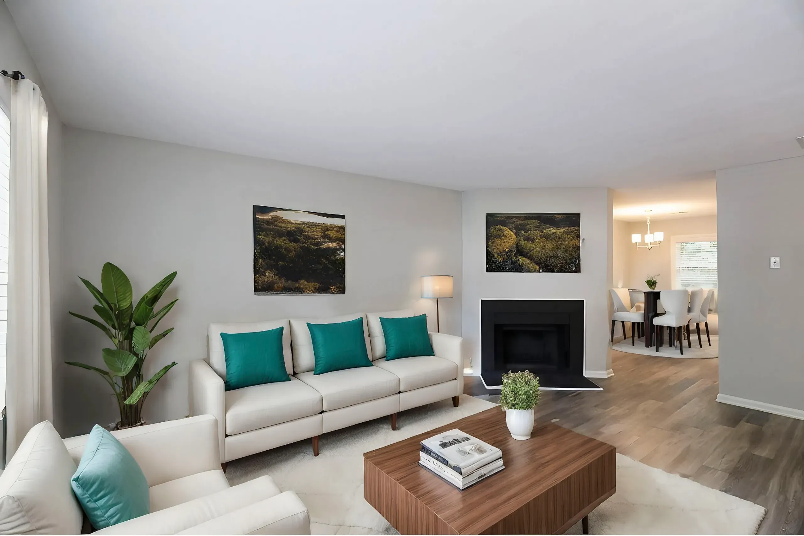 Living room, cream sectional sofa, teal accent pillows, fireplace with black surround, wood-style plank flooring, nature artwork