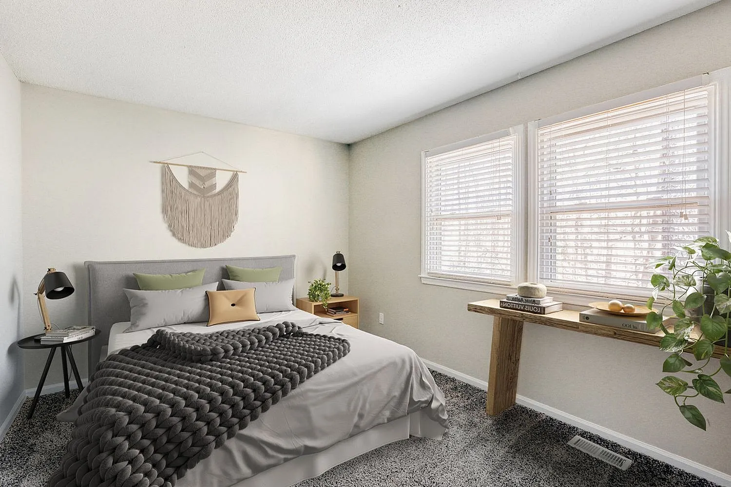 Primary bedroom, gray upholstered headboard, charcoal waffle weave bedding, gray carpet, wood-style plank desk