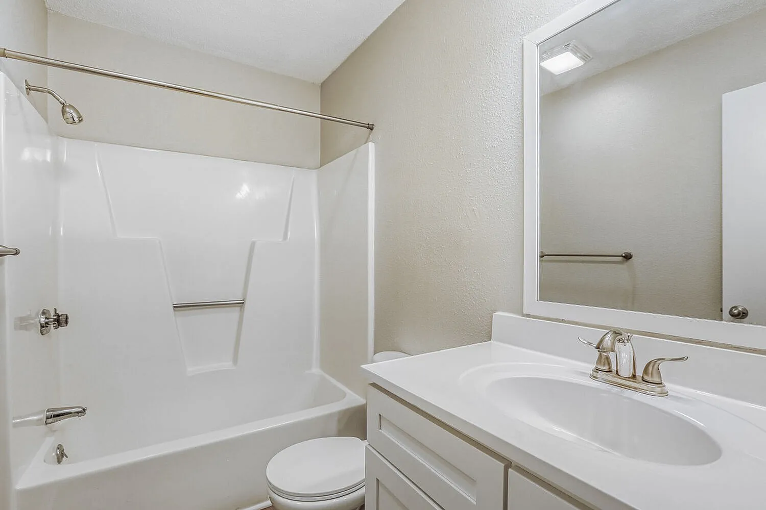 Bathroom, white vanity with oval sink, framed mirror, white subway tile shower surround, toilet