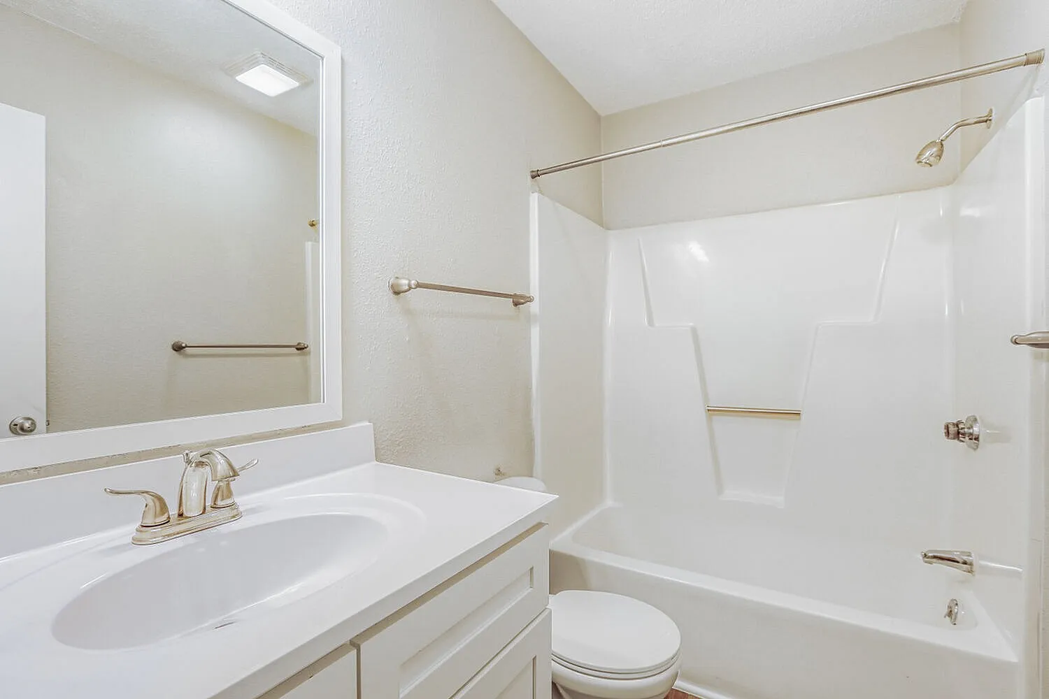 Bathroom, white vanity with oval sink, large mirror, white subway tile shower surround with brushed nickel hardware