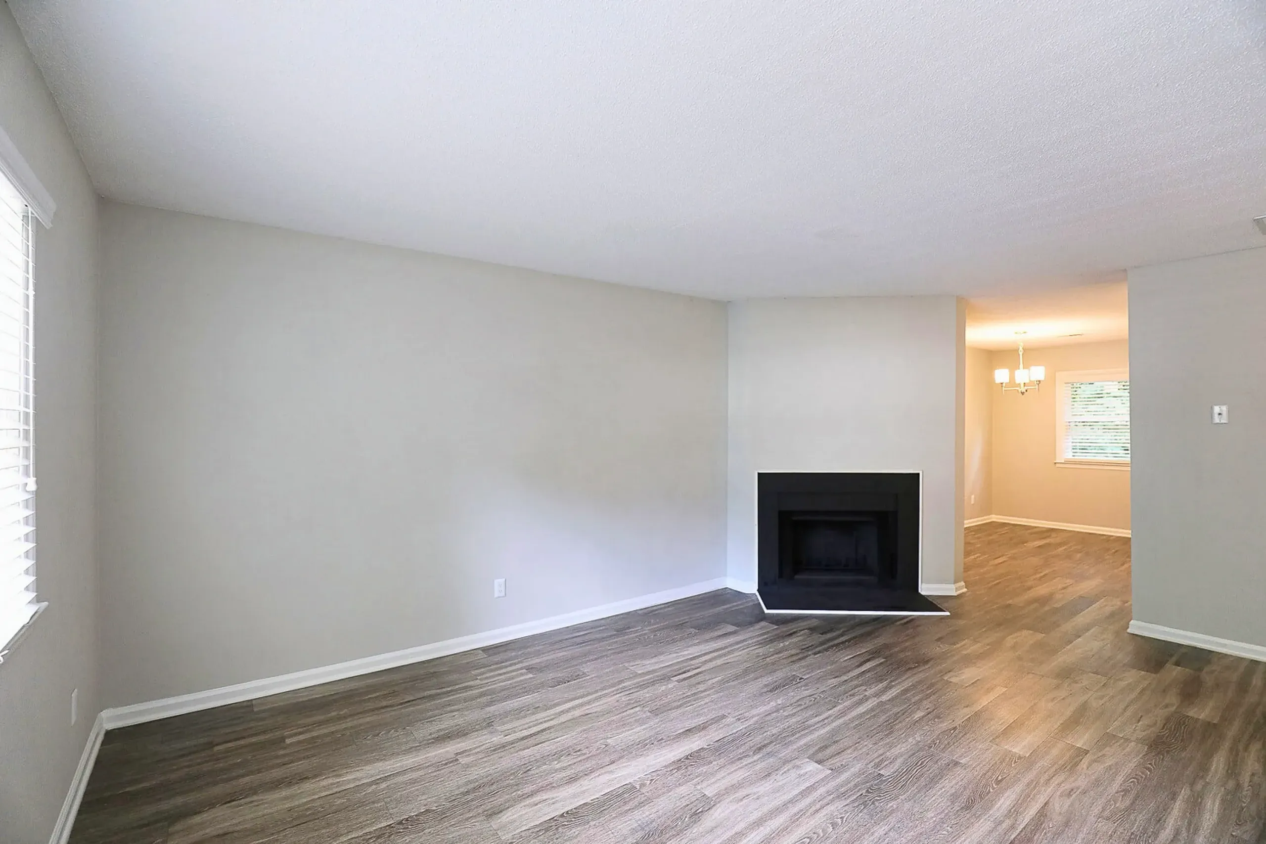 Living room with wood-style plank flooring, fireplace, entry to hallway