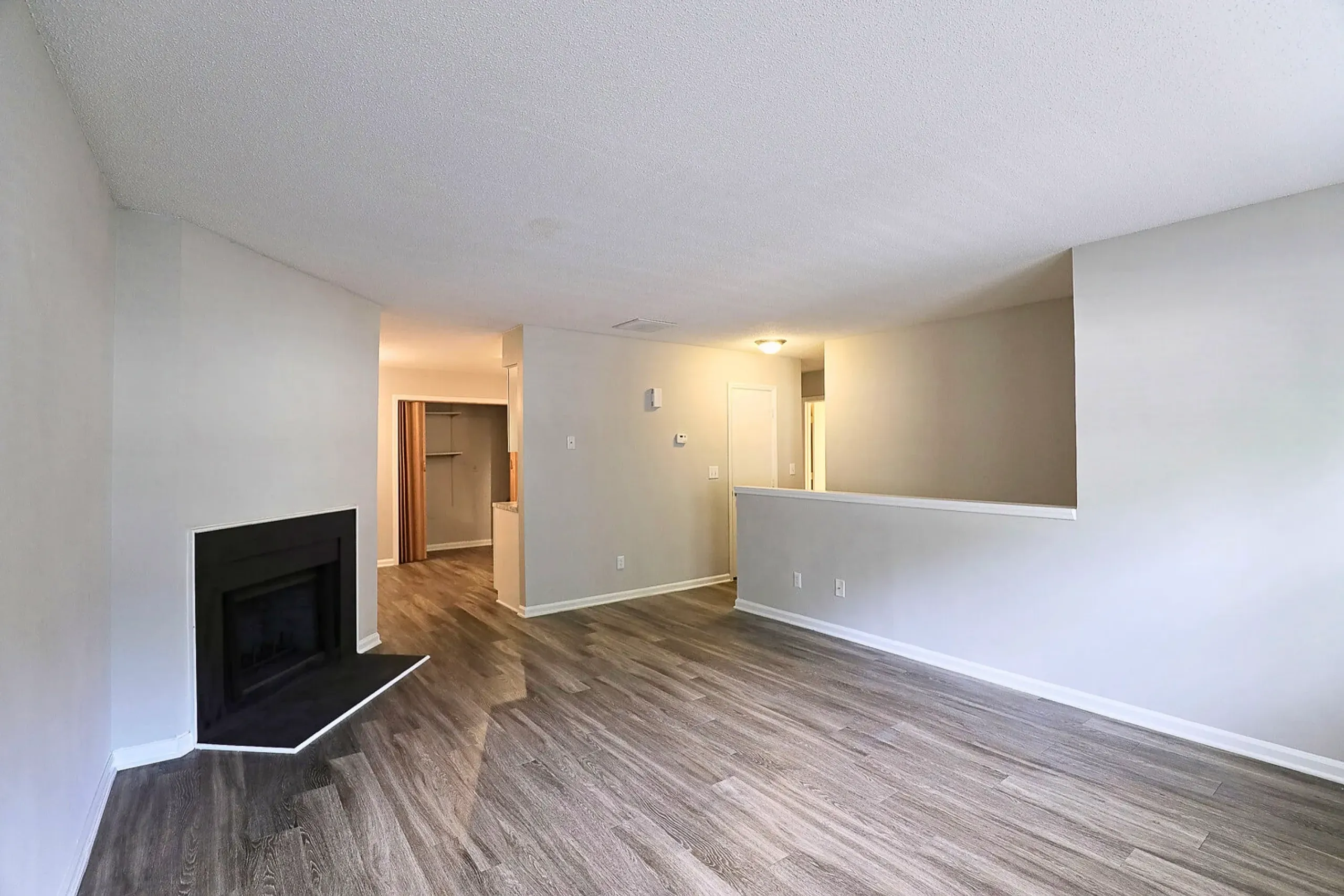 Open concept living area, wood-style plank flooring, fireplace, kitchen opening