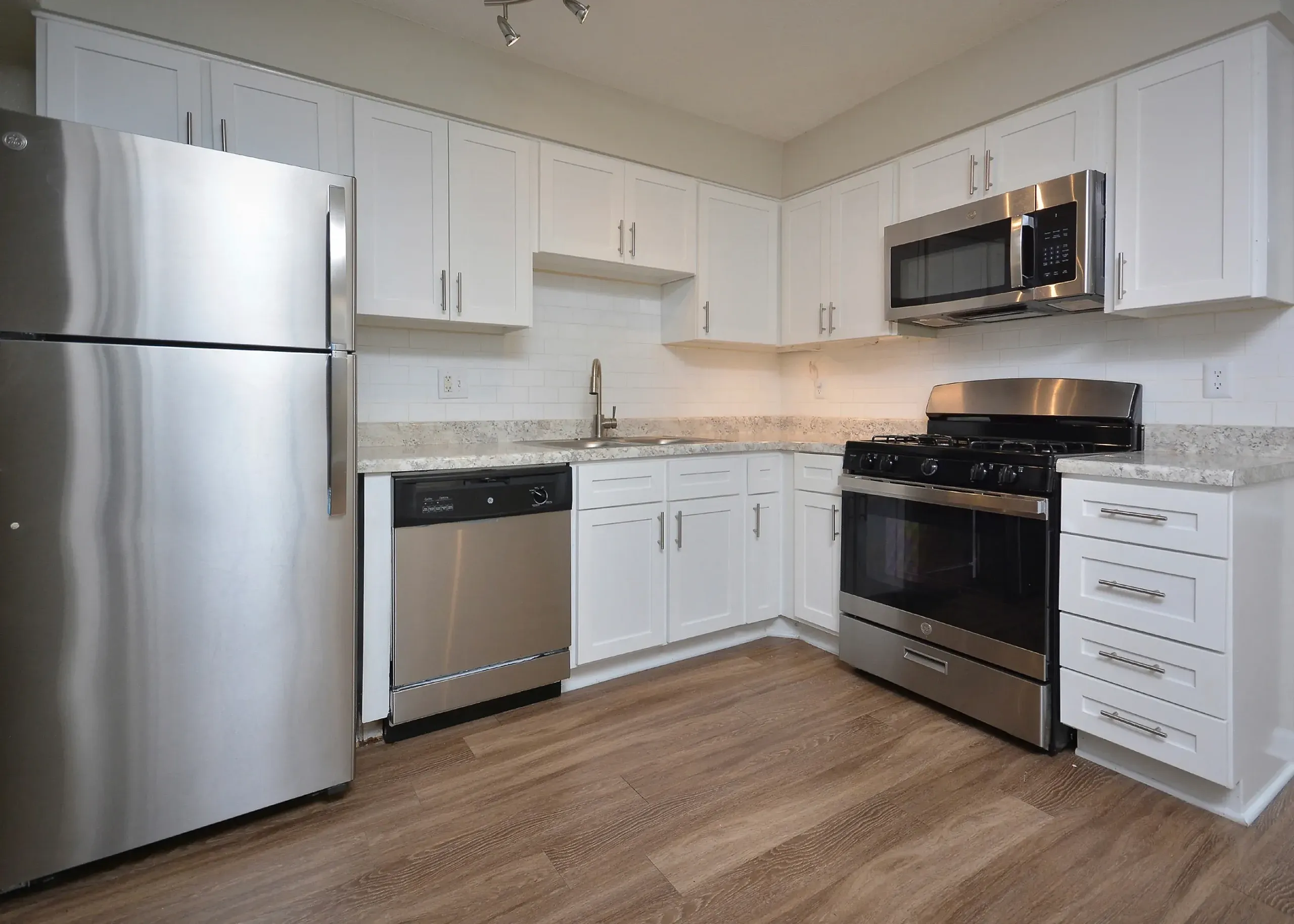 Kitchen, white shaker cabinetry, light quartz countertops, stainless appliances, wood-style plank flooring