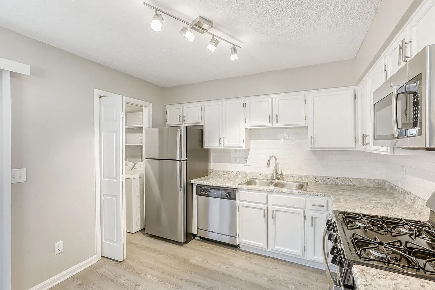 Kitchen, white shaker cabinetry, granite countertops, stainless steel appliances, wood-style plank flooring
