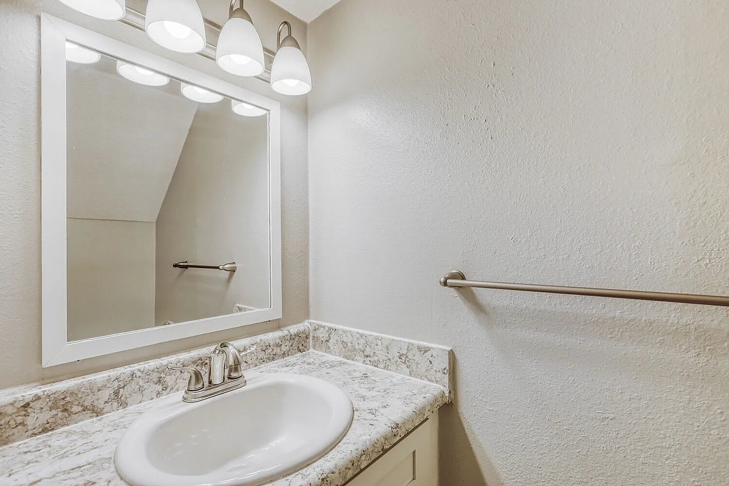 Bathroom, speckled granite countertops, framed mirror with vanity lighting, oval sink