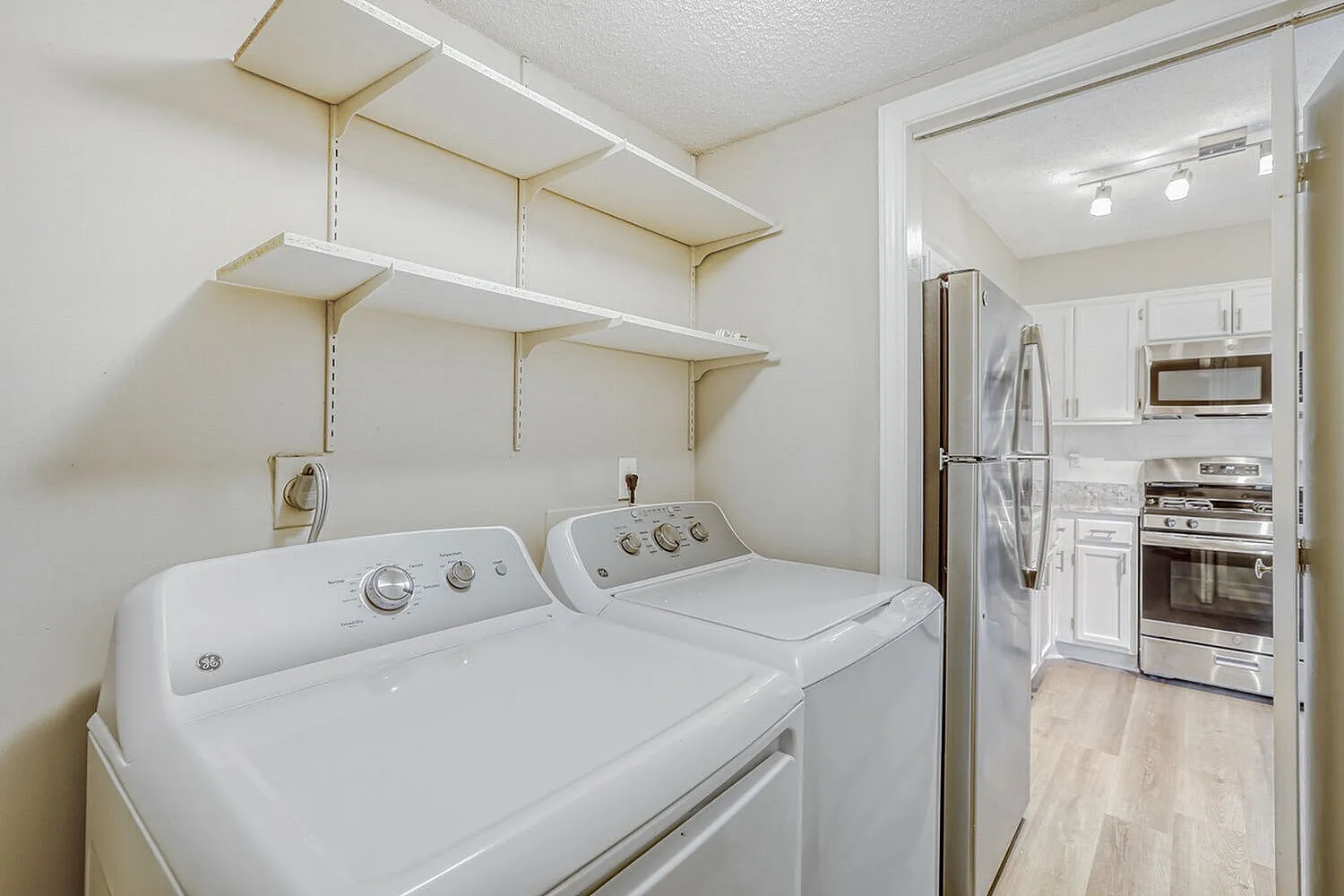Laundry room, front-load washer and dryer, floating wood shelving, utility sink, wood-style plank flooring