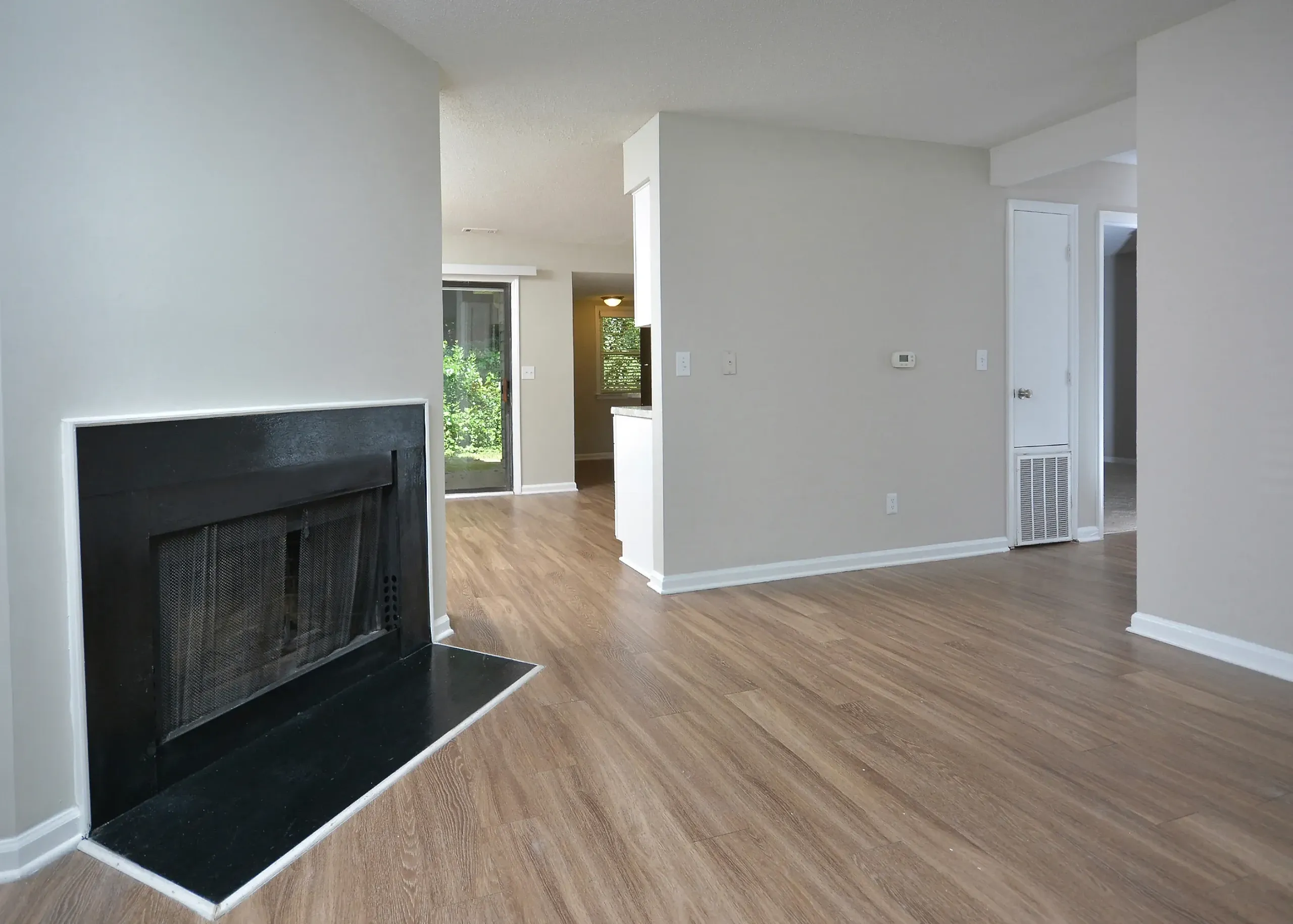 Living room, black fireplace surround, wood-style plank flooring, open layout, natural light