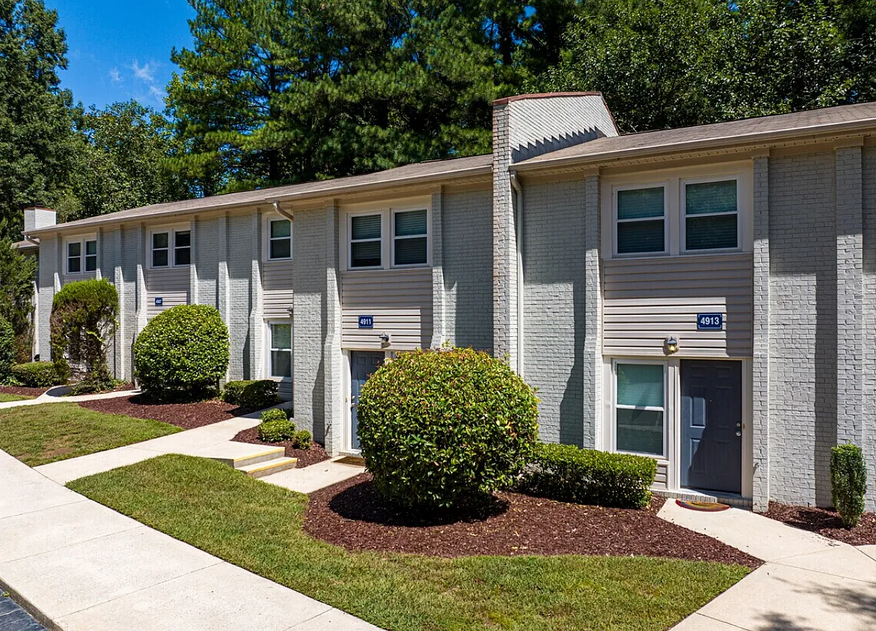 Townhome exterior, gray siding, brick accents, rounded hedge landscaping, manicured lawn