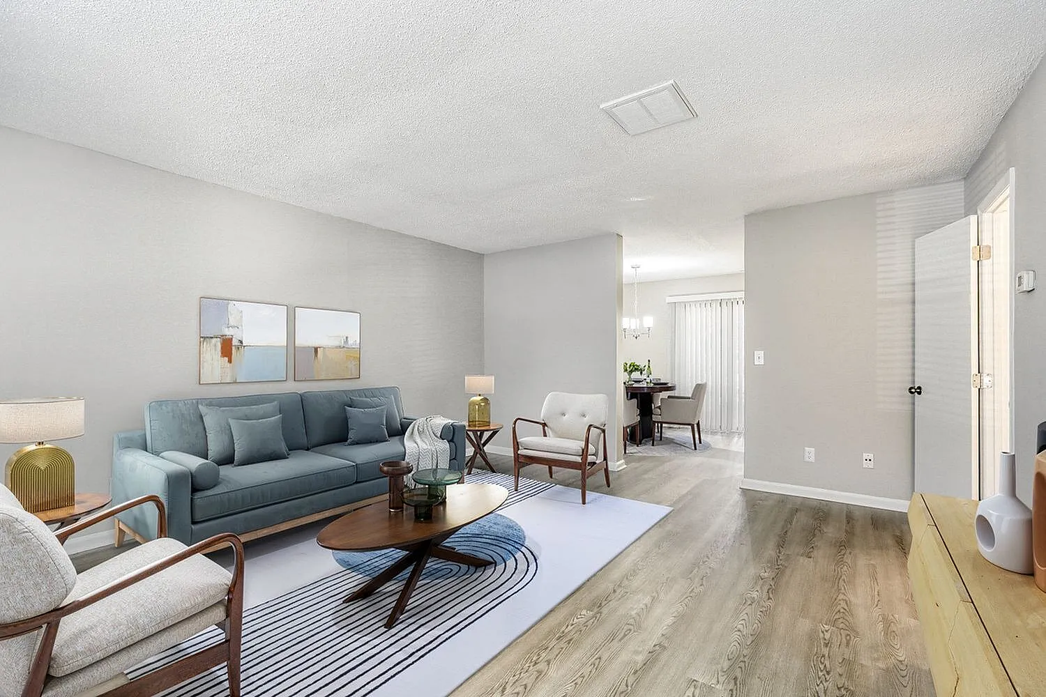 Living room, blue sofa, cream accent chair, wood-style plank flooring, area rug